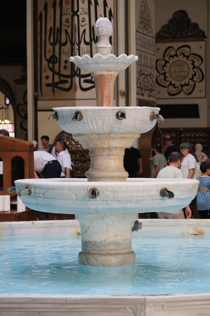 Beautiful marble fountain in a historic mosque interior with intricate calligraphy decor.